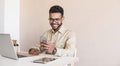 Happy smiling young man using smart phone and laptop at office. Handsome businessman working on computer and  texting phone Royalty Free Stock Photo