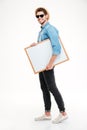 Happy smiling young man walking and holding blank whiteboard Royalty Free Stock Photo