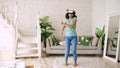 Happy smiling young mixed race girl getting experience using VR headset glasses of virtual reality and dancing at home Royalty Free Stock Photo