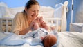 Happy smiling young mother looking at her newborn baby sleeping in bed at night Royalty Free Stock Photo