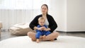 Happy smiling young mother teaching her little baby son doing yoga asana while practising yoga. Family healthcare, active Royalty Free Stock Photo