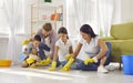 Young parents with children cleaning floor together in the living room at home Royalty Free Stock Photo