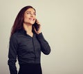 Happy smiling young positive woman with long curly hairstyle in business office clothing talking on mobile phone and looking up. Royalty Free Stock Photo