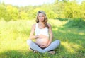 Happy smiling young pregnant woman sitting on grass doing yoga Royalty Free Stock Photo