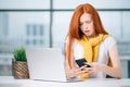 Happy redhead girl send an sms message to friend while working at modern office Royalty Free Stock Photo