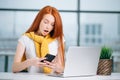 Happy redhead girl send an sms message to friend while working at modern office Royalty Free Stock Photo