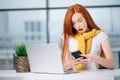 Happy redhead girl send an sms message to friend while working at modern office Royalty Free Stock Photo