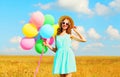 Happy smiling young woman with an air colorful balloons enjoying a summer day on field blue sky background Royalty Free Stock Photo