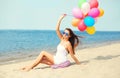 Happy smiling young woman with colorful balloons on beach Royalty Free Stock Photo