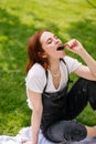 Happy smiling young woman eating cherry of the park lawn Royalty Free Stock Photo