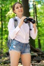 Happy young woman as a backpacker in forest with binoculars