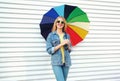 Happy smiling young woman holding colorful umbrella in hands on white