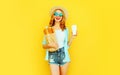 happy smiling young woman holding paper bag with long white bread baguette, coffee cup, wearing straw hat, shorts on colorful Royalty Free Stock Photo