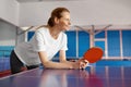 Happy smiling young woman holding racket in hand leaning over tennis table Royalty Free Stock Photo