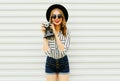 Happy smiling young woman holding vintage film camera in black round hat, shorts, white striped shirt on white wall Royalty Free Stock Photo