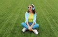 Happy smiling young woman listening to music in headphones while lying on grass in summer park Royalty Free Stock Photo