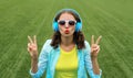 Happy smiling young woman listening to music in headphones while lying on grass in summer park Royalty Free Stock Photo