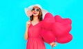 Happy smiling young woman with lollipop, pink heart shaped air balloons on colorful blue background Royalty Free Stock Photo