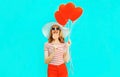 Happy smiling young woman with lollipop, red heart shaped air balloons in summer straw hat and shorts on colorful Royalty Free Stock Photo