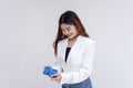 A happy and smiling young woman looking down at a small blue gift in her hands. Isolated on a white background Royalty Free Stock Photo