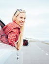 Happy smiling young woman looks out from car window Royalty Free Stock Photo