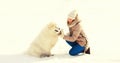 Happy smiling young woman owner giving hand to paw high five with white Samoyed dog in winter park