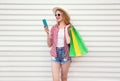 Happy smiling young woman with phone, holding colorful shopping bags in summer round straw hat, checkered shirt, shorts on white Royalty Free Stock Photo