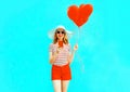 Happy smiling young woman with phone, red heart shaped air balloons in summer straw hat and shorts Royalty Free Stock Photo