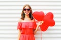 Happy smiling young woman in red dress and sunglasses with air balloons heart shape over white Royalty Free Stock Photo