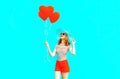 Happy smiling young woman with red heart shaped air balloons in summer straw hat and shorts on colorful Royalty Free Stock Photo