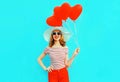 Happy smiling young woman with red heart shaped air balloons in summer straw hat and shorts on colorful blue Royalty Free Stock Photo