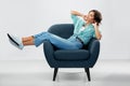 Happy smiling young woman sitting in armchair Royalty Free Stock Photo