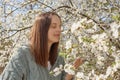 Happy smiling young woman smelling spring flowers at garden enjoying pleasant fresh aroma looking at beautiful cheery blossom with Royalty Free Stock Photo