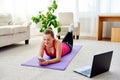 Happy smiling young woman in sportwear resting on mat on floor and using mobile cellphone at home, copy space. Royalty Free Stock Photo