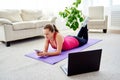 Happy smiling young woman in sportwear resting on mat on floor and using mobile cellphone at home, copy space. Royalty Free Stock Photo