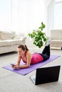 Happy smiling young woman in sportwear relaxing on mat on floor and using mobile cellphone at home, copy space. Full length body. Royalty Free Stock Photo