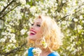 Happy smiling young woman with spring flowers at garden. Outdoor fashion photo of beautiful young woman surrounded by Royalty Free Stock Photo