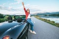 Happy smiling young woman stay near the cabriolet car on the mountain road Royalty Free Stock Photo