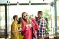 Happy, smiling, young woman in stylish clothes meeting with friends at cafe, having funny, joyful time. Blurred people Royalty Free Stock Photo