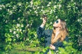 Happy smiling young woman in sunglasses and a knitted jacket enjoying spring flowers in the garden Royalty Free Stock Photo