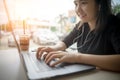 Happy smiling young woman typing on laptop computer using headphones listening music in coffee shop Royalty Free Stock Photo