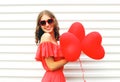 Happy smiling young woman wearing red dress and sunglasses with air balloons heart shape over white Royalty Free Stock Photo