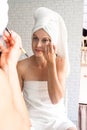 Happy smiling young woman in white bath towels doing morning make up looking at the mirror Royalty Free Stock Photo