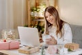 Happy and smiling young woman wrapping and preparing Christmas gifts, typing at laptop and having online video chat Royalty Free Stock Photo