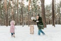 Happy and smilling young mother and her little daughter having fun outside, in winter park