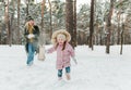 Happy and smilling young mother and her little daughter having fun outside, in winter park