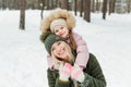Happy and smilling young mother and her little daughter in winter park outside