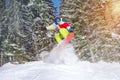 Snowboarder backcountry jump offpiste against frozen forest