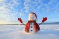 Happy snowman in hat, scarf, red gloves with ice pikestaff is standing on the snow lawn. Unbelievable sunrise. Mountains landscape