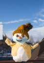 Happy snowman in a knitted orange hat  sweater and medical mask with a smile painted on it Royalty Free Stock Photo